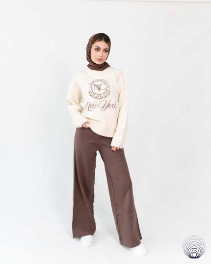 بافت زنانه کرمی از برند Bershka با یقه گرد و آستین بلند، ست شده با شلوار بافت قهوه‌ای، مناسب استایل اسپرت پاییزی و زمستانی